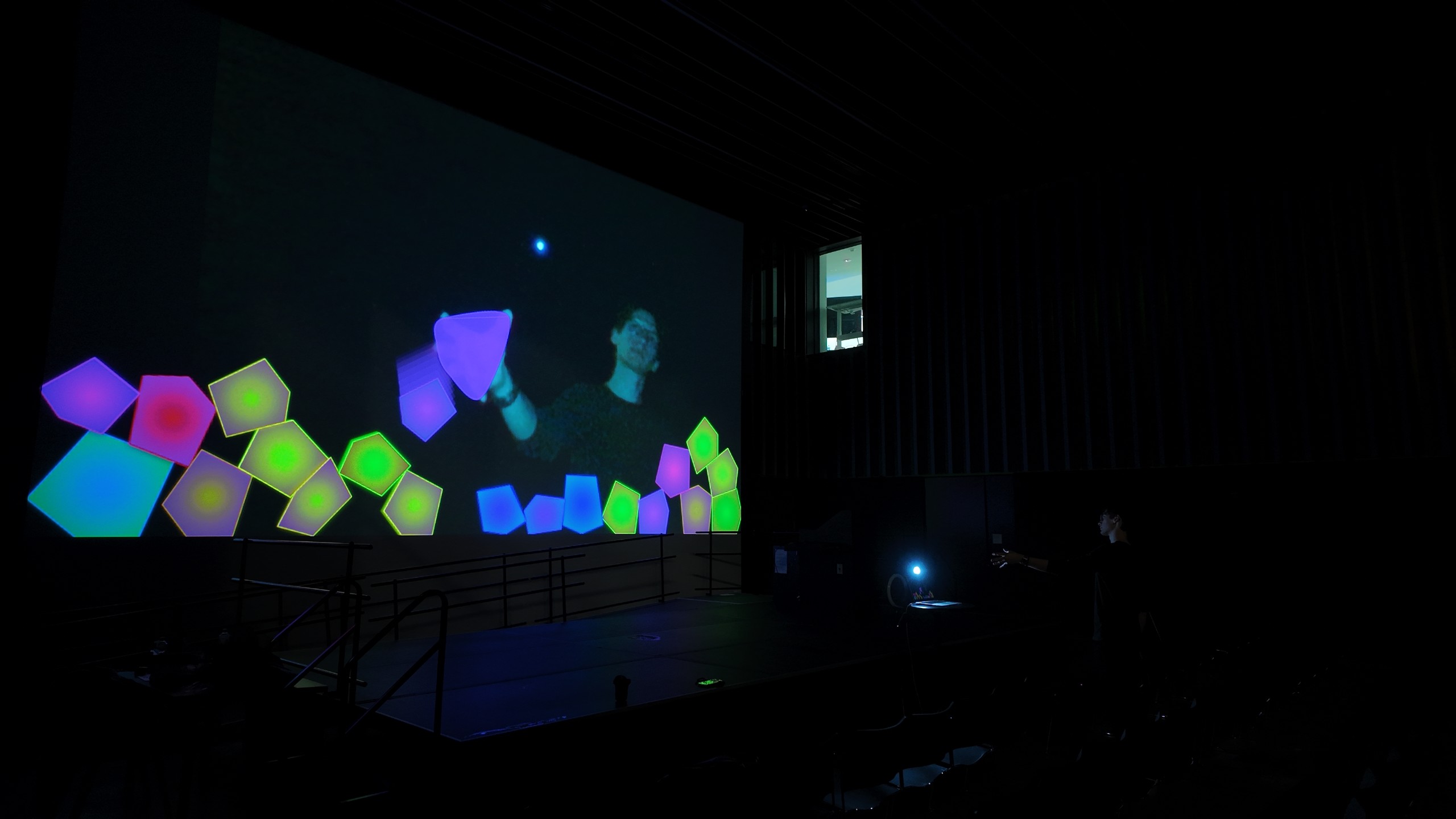 Participant shaping luminous communal blobs across a full-scale projection